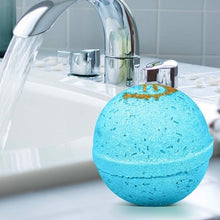 Blue bath bomb with gold design on a bathtub ledge near chrome faucet
