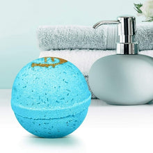 Blue bath bomb with gold design beside a white towel and soap dispenser