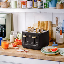 Black four-slice toaster with toast in its slots and gold levers