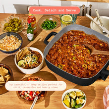 Black electric skillet filled with chili, with deep pan and side handles