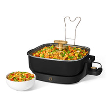 Black electric skillet filled with rice and vegetables, with glass lid propped open