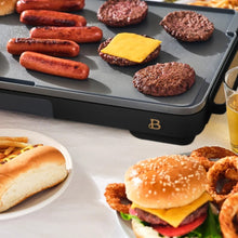 XL electric griddle cooking sausages and burgers on its gray nonstick surface