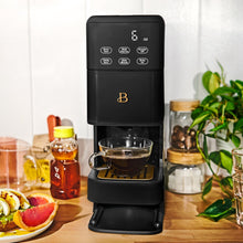 Black single-serve coffee maker brewing into a glass cup