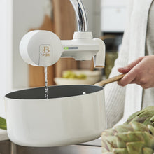 White faucet filter system dispensing water into a pot