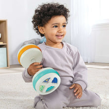 Bouncy barbell baby toy in teal and white held by child, roller end visible