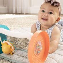 Baby playing with activity mirror, orange-and-teal mirror base on quilt