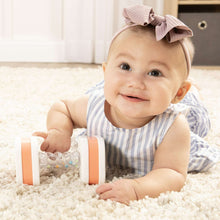 Orange-and-white twist-and-shake dumbbell baby toy with clear bead rattle, front view