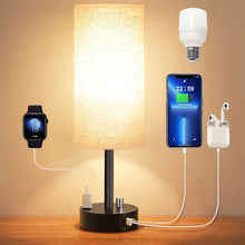 Bedside table lamp with linen fabric shade and black base, warm light