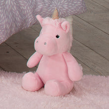 Pink unicorn plush stuffed animal sitting on a soft rug