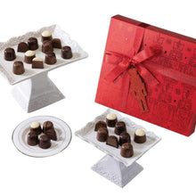 Assorted chocolate truffles on plates with a red ribboned gift box