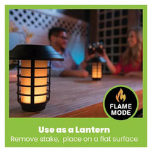 Solar stake lantern light in flame mode with warm glow on outdoor deck surface.