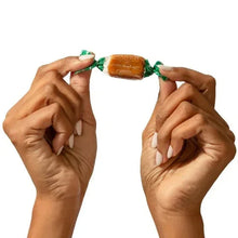 Béquet Celtic sea salt caramels, hands holding a green-wrapped caramel