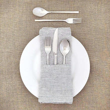 Stainless steel flatware pieces arranged on a folded cloth napkin