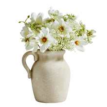 Artificial wildflower arrangement with white blooms and green stems in beige ceramic jug vase
