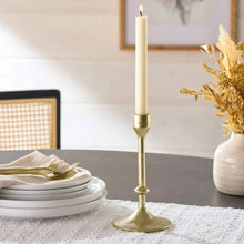 Gold cast iron taper candle holder with flared round foot and slender stem