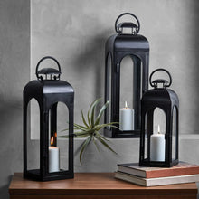Black metal lantern candle holder with arched top handle and glass panels