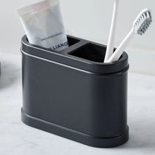 Black metal toothbrush holder with two compartments holding toothbrushes