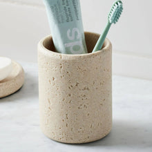 Speckled beige toothbrush holder with toothpaste tube and toothbrushes