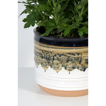Round ceramic planter close-up with blue-gray top and greenish speckled drip glaze