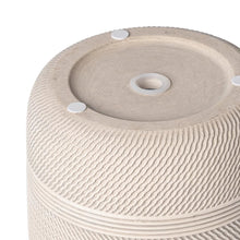 Underside view of round textured ceramic planter with drain openings