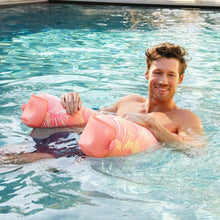 Pink palm-pattern sling pool float with padded arm tubes and curved head rest