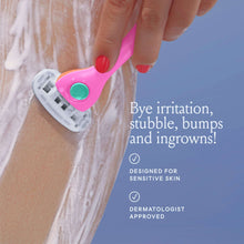Pink razor in hand with blade cartridge on wet skin and shaving foam