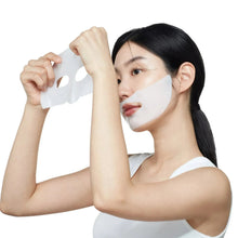 Facial sheet mask on face, white sheet held up by hands