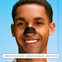 Black charcoal pore strip applied to a man's nose, smiling face