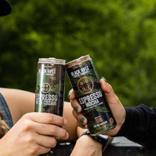 Two Black Rifle Coffee Company espresso cans held by hands, one with Cream label