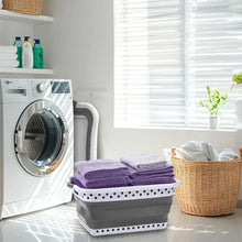Collapsible laundry basket filled with towels, gray bin and white perforated trim