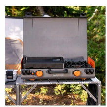 Propane camping griddle with open lid, orange control knobs and side burner