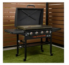 Black outdoor griddle with open hood, front burner knobs, and side shelf supports
