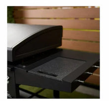Close-up of black griddle cooking surface under open hood with textured grease tray