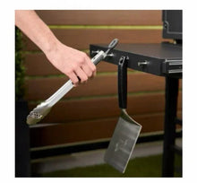 Side shelf tool hooks holding a spatula and ladle beside the griddle