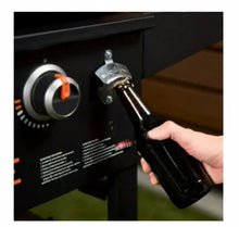 Griddle control knob panel with hand holding an ignition tool near the burner controls