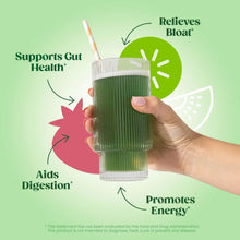 Hand holding a tall glass of green smoothie with a straw