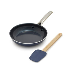 Ceramic nonstick frying pan in dark blue with long wooden spatula and metal handle
