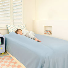 White toddler bed bumper along the mattress edge beside a sleeping child