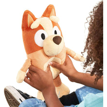 Talking Bingo plush held by child, orange and cream dog with stitched facial details