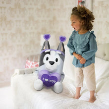 Jumbo plush dog with purple heart and “I love you” patch beside a standing child