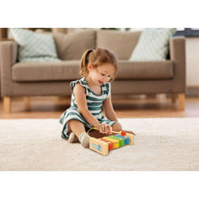 Child playing a colorful wooden xylophone with mallet on living room floor