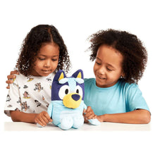 Bluey plush dog, light blue with navy ears and yellow muzzle, held by children