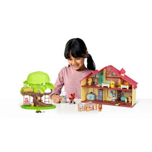 Child playing with red-roof house playset and green barbecue tree with figures