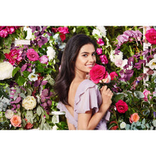 Smiling woman standing among pink and white flowers