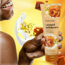 Bodycology caramel indulgence body cream tube held in a hand with whipped lotion splash
