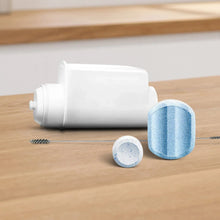 White cleaning cartridge with blue filter pads and a metal brush on wood.