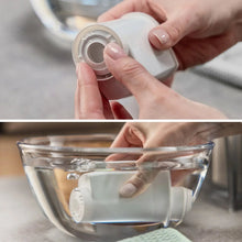 Hands installing a small metal filter screen into an espresso machine component.