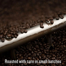 Dark roasted whole coffee beans spilling from a tray