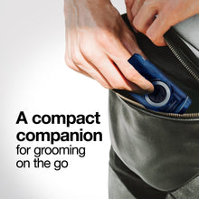 Blue compact electric shaver in hand with foil head and circular dial.