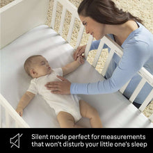 White infrared thermometer held near a baby on a bed